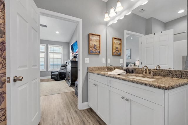 bathroom with wood-type flooring, vanity, and vaulted ceiling