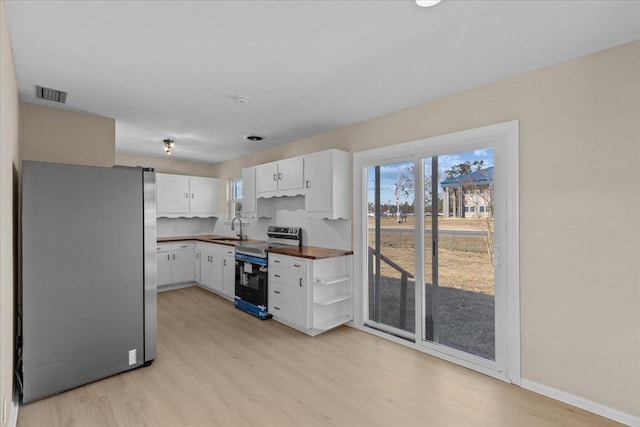 kitchen with white cabinets, light wood-type flooring, appliances with stainless steel finishes, and sink