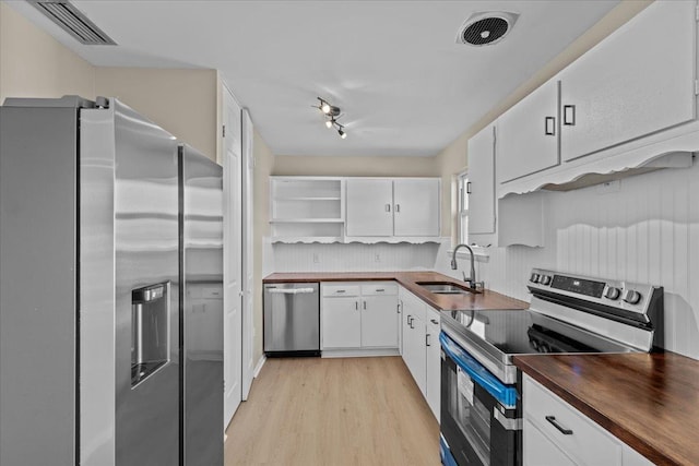 kitchen with white cabinetry, appliances with stainless steel finishes, backsplash, light hardwood / wood-style flooring, and sink