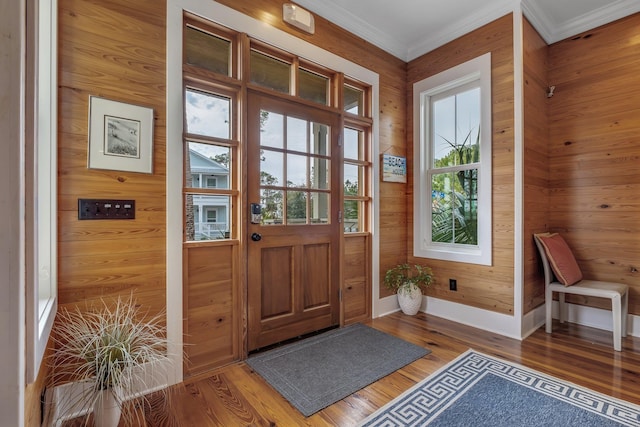 doorway to outside with wood walls, crown molding, and wood-type flooring