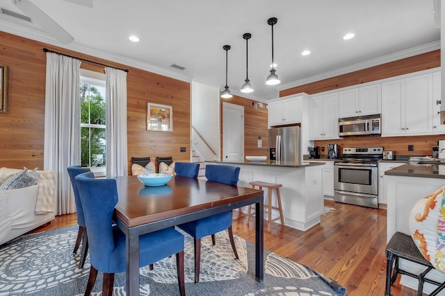 dining area with crown molding, wood walls, and dark hardwood / wood-style floors