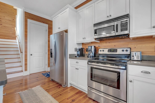 kitchen featuring white cabinetry, ornamental molding, appliances with stainless steel finishes, and light hardwood / wood-style flooring