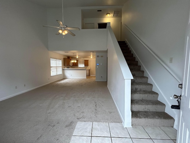 stairs featuring a high ceiling, ceiling fan, and carpet flooring