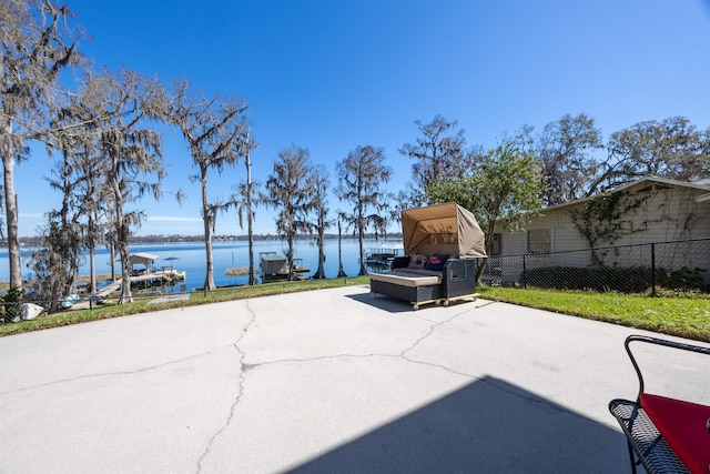 view of patio / terrace featuring a carport, fence, a water view, and driveway