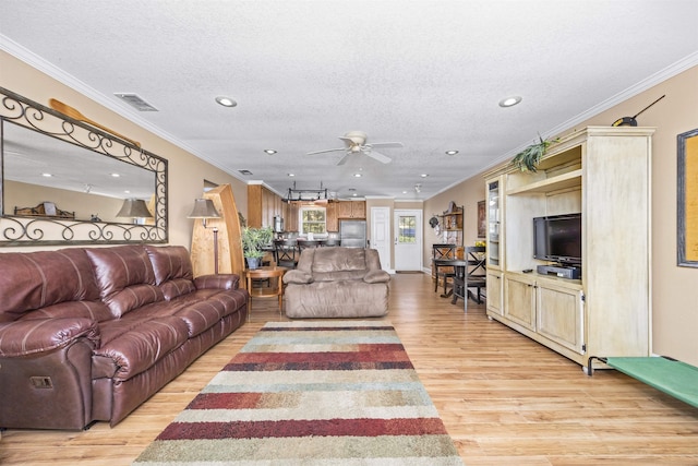 living area with visible vents, light wood-style floors, and ornamental molding