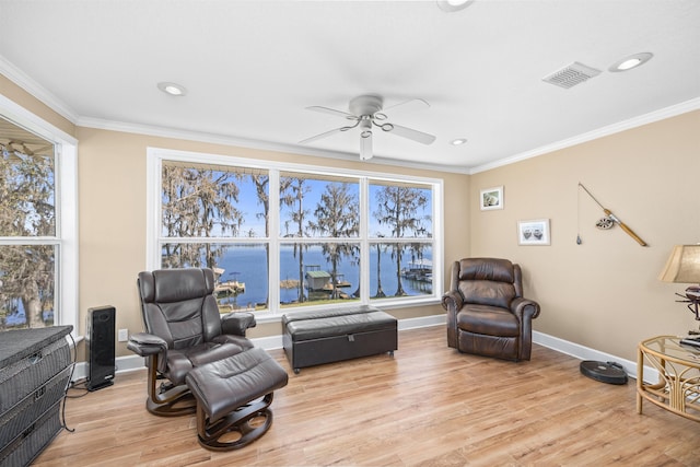 sitting room with plenty of natural light, light wood-style floors, baseboards, and ornamental molding