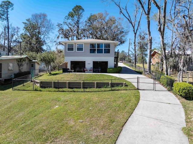 view of front of house with a fenced front yard, driveway, and a front lawn