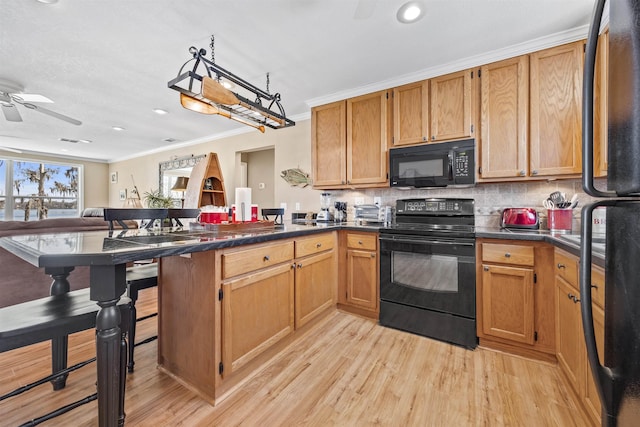 kitchen featuring a peninsula, black appliances, crown molding, dark countertops, and tasteful backsplash