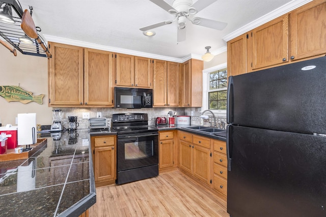 kitchen with a sink, decorative backsplash, light wood-style floors, and black appliances