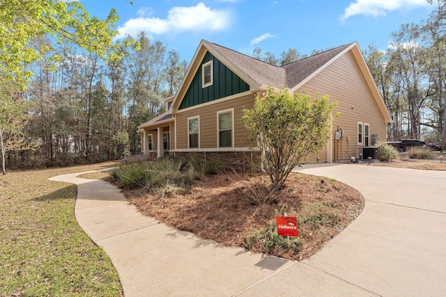 view of side of home with central air condition unit, driveway, and board and batten siding