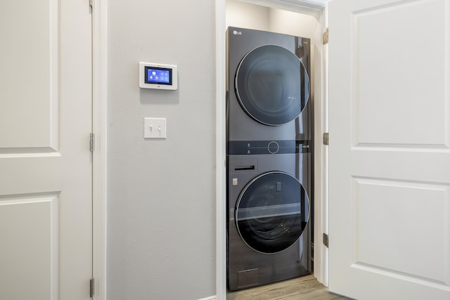 laundry room featuring stacked washer and clothes dryer and light wood-type flooring