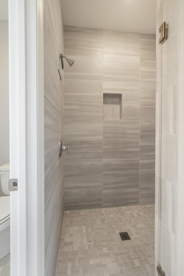 bathroom with toilet and tiled shower