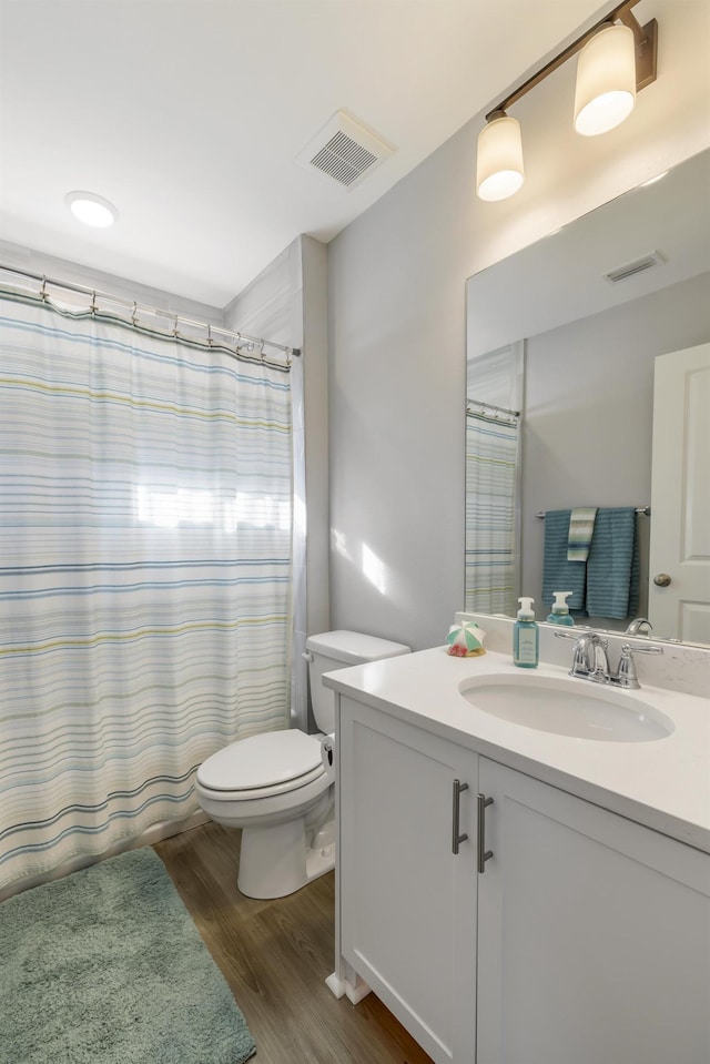 bathroom with walk in shower, vanity, toilet, and hardwood / wood-style floors