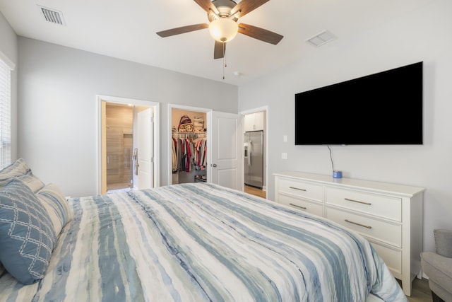 bedroom featuring ensuite bathroom, a walk in closet, ceiling fan, stainless steel fridge with ice dispenser, and a closet