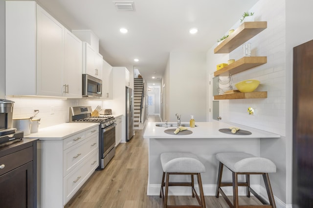 kitchen with tasteful backsplash, white cabinetry, a kitchen breakfast bar, kitchen peninsula, and stainless steel appliances