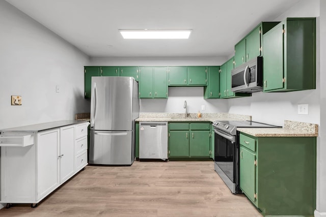 kitchen featuring light wood-type flooring, green cabinets, stainless steel appliances, and sink