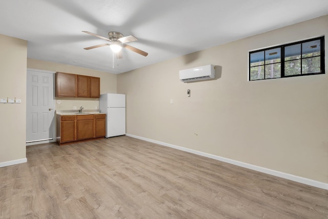 kitchen with white fridge, sink, a wall mounted AC, ceiling fan, and light hardwood / wood-style flooring