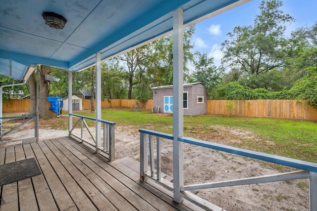 wooden terrace featuring a yard and a shed