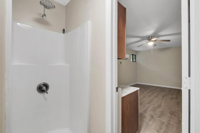 bathroom featuring ceiling fan, a shower, and hardwood / wood-style flooring