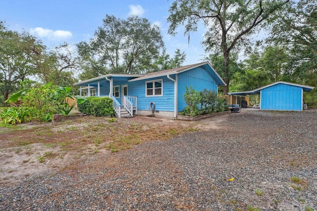 view of front facade featuring a porch, a carport, and an outdoor structure