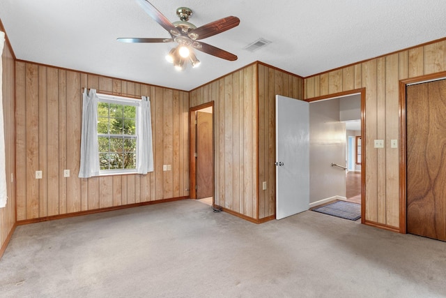 unfurnished bedroom with light colored carpet, ornamental molding, and wooden walls