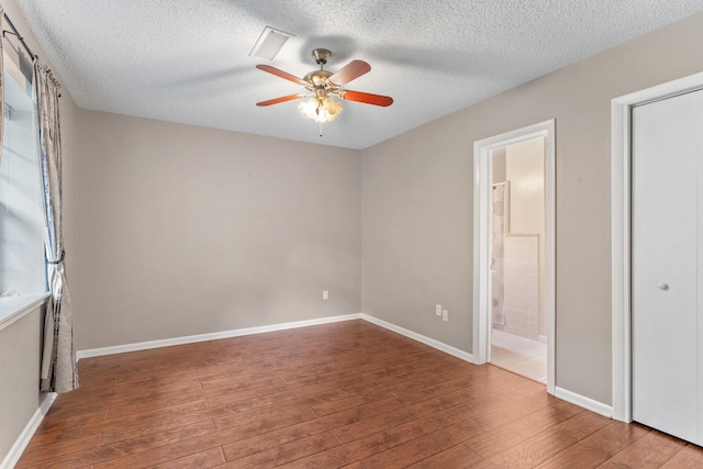 unfurnished bedroom featuring ceiling fan, ensuite bath, wood-type flooring, and a textured ceiling