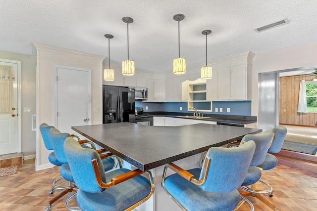 kitchen with sink, white cabinetry, hanging light fixtures, black appliances, and a textured ceiling