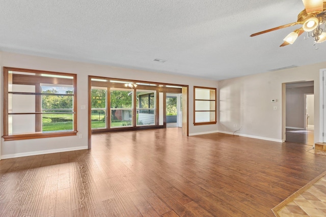 unfurnished room with a healthy amount of sunlight, dark hardwood / wood-style floors, and a textured ceiling