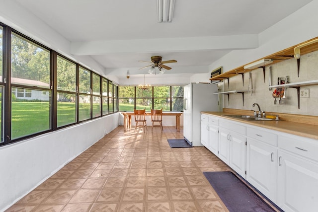 unfurnished sunroom with sink, ceiling fan with notable chandelier, and beamed ceiling