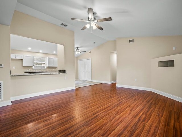 unfurnished living room with ceiling fan, dark hardwood / wood-style flooring, vaulted ceiling, and sink