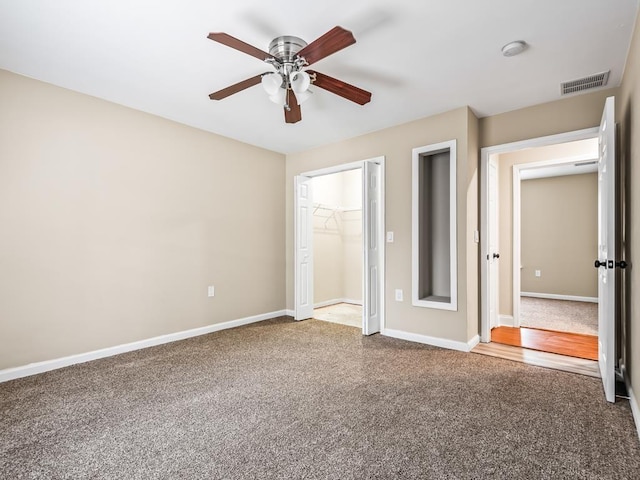 unfurnished bedroom with carpet flooring, ceiling fan, a spacious closet, and a closet