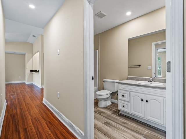 bathroom featuring hardwood / wood-style floors, vanity, vaulted ceiling, and toilet