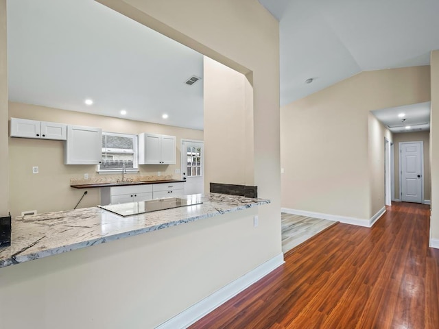 kitchen featuring kitchen peninsula, white cabinetry, and light stone counters