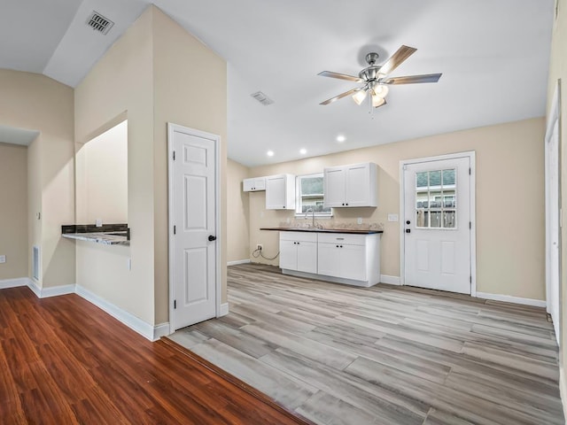 kitchen with white cabinetry, ceiling fan, light hardwood / wood-style floors, and vaulted ceiling