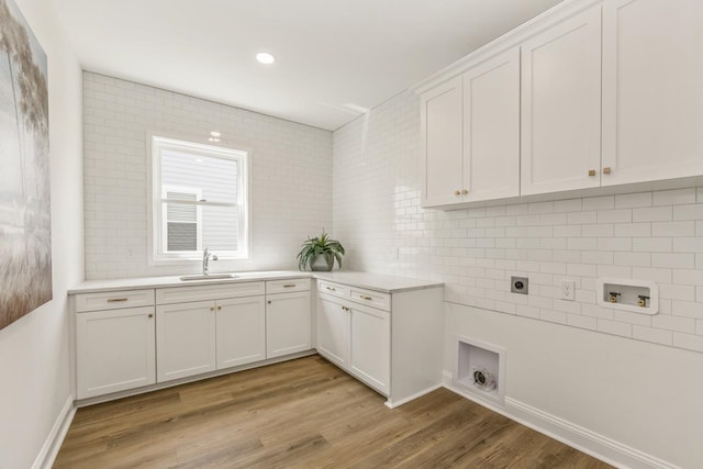 clothes washing area with cabinet space, light wood finished floors, electric dryer hookup, washer hookup, and a sink