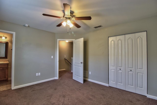 unfurnished bedroom featuring ensuite bathroom, a closet, ceiling fan, and dark carpet