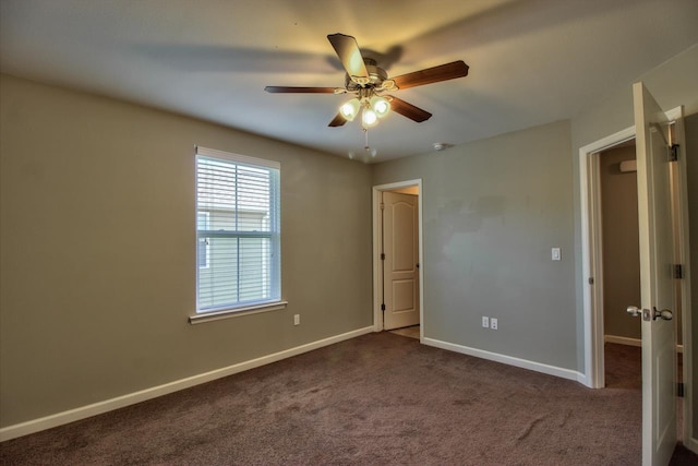 empty room with dark colored carpet and ceiling fan