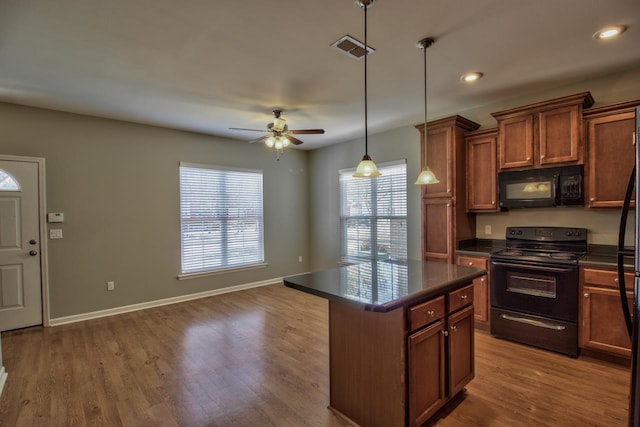 kitchen with dark hardwood / wood-style flooring, a center island, black appliances, ceiling fan, and pendant lighting