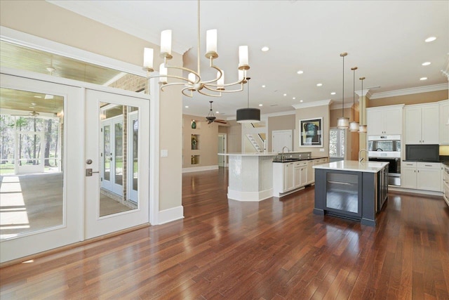3621 Moody Trl, Tallahassee, FL 32309 - kitchen featuring a sink, an island with sink, dark wood finished floors, crown molding, and pendant lighting