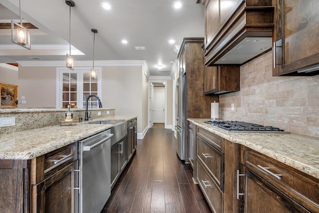 kitchen with pendant lighting, sink, dark brown cabinets, stainless steel appliances, and light stone countertops