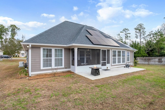 back of property with a sunroom, a yard, a patio area, and solar panels