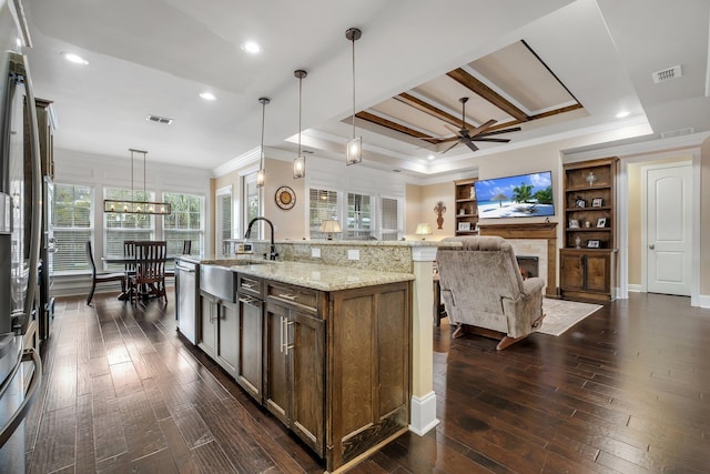 kitchen featuring pendant lighting, sink, a large island, light stone counters, and dark wood-type flooring