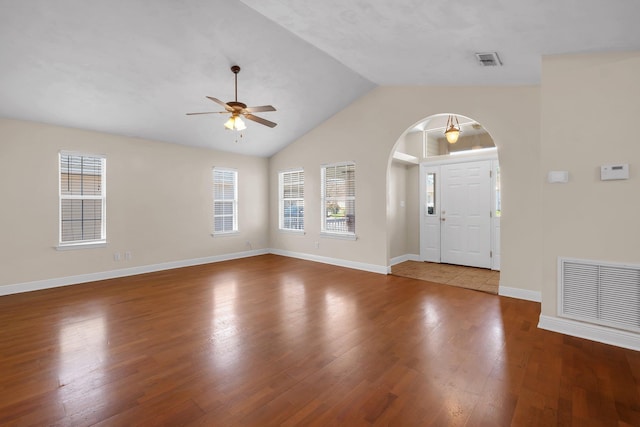 foyer entrance with baseboards, visible vents, arched walkways, and wood finished floors