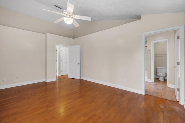 unfurnished bedroom with visible vents, ensuite bathroom, vaulted ceiling, wood finished floors, and baseboards