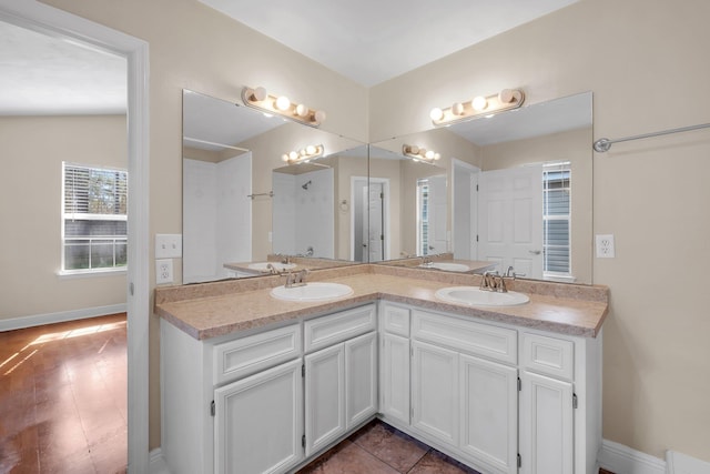 bathroom featuring a sink, baseboards, and double vanity