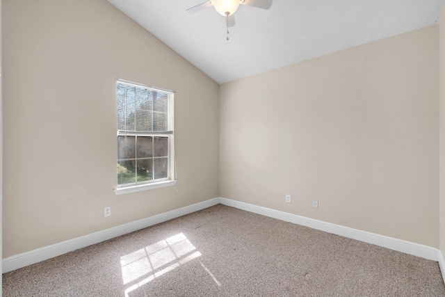 carpeted spare room with vaulted ceiling, a ceiling fan, and baseboards