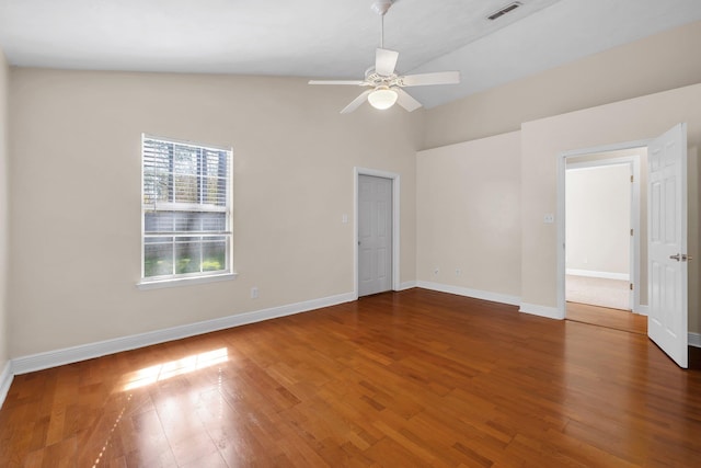 spare room with lofted ceiling, visible vents, ceiling fan, wood finished floors, and baseboards