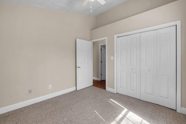 unfurnished bedroom featuring carpet floors, lofted ceiling, a closet, a ceiling fan, and baseboards