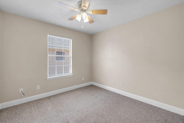 carpeted spare room featuring baseboards and a ceiling fan