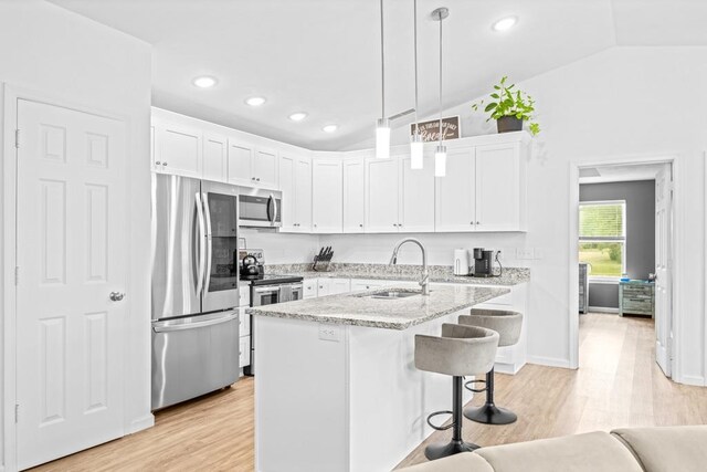 kitchen featuring white cabinets, lofted ceiling, sink, and appliances with stainless steel finishes